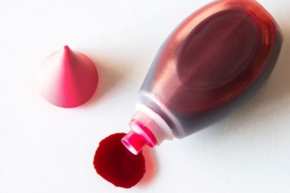a bottle of red dye spilling onto a white surface
